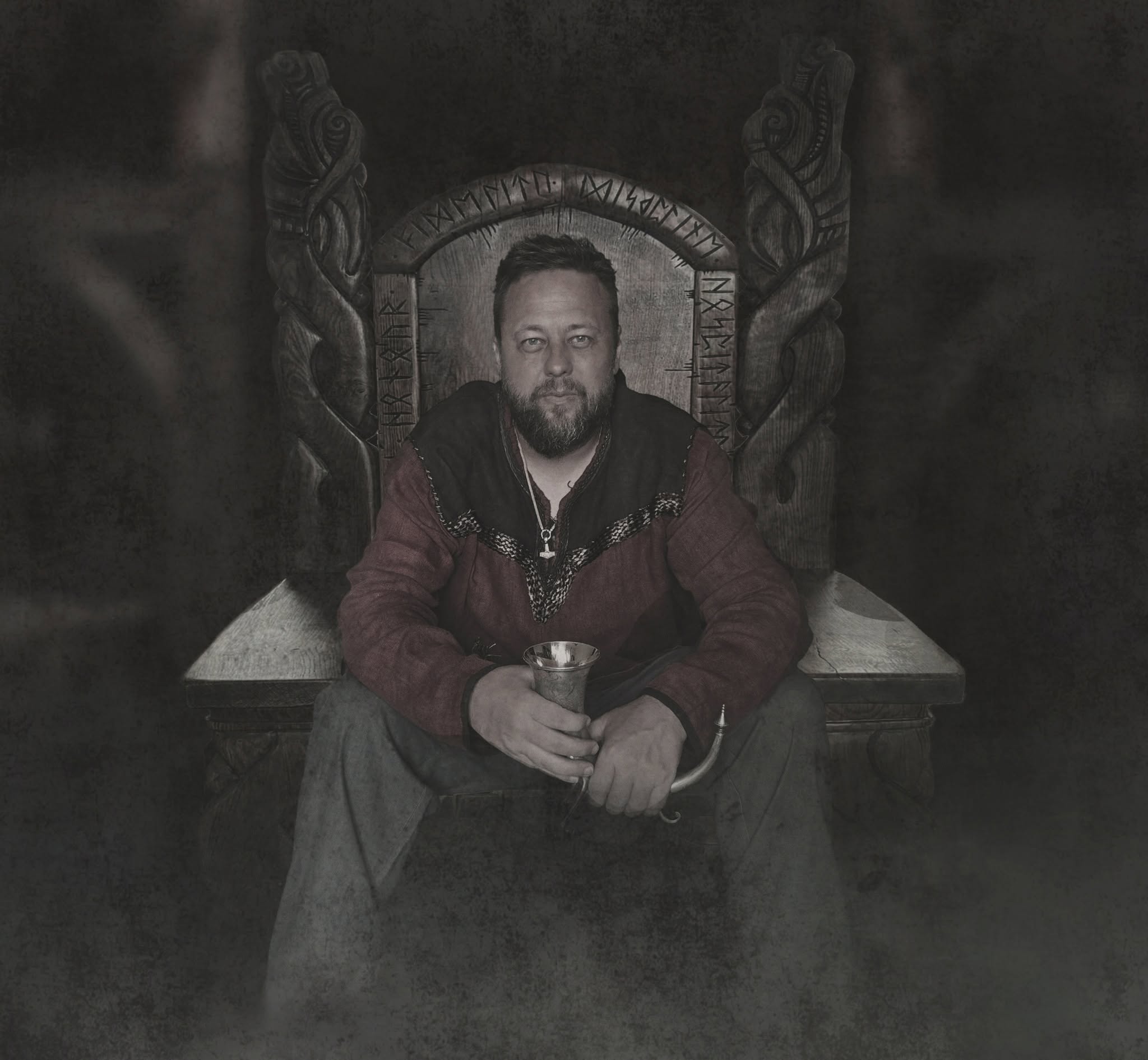 Danheim seated on a rune-carved wooden throne holding a drinking horn